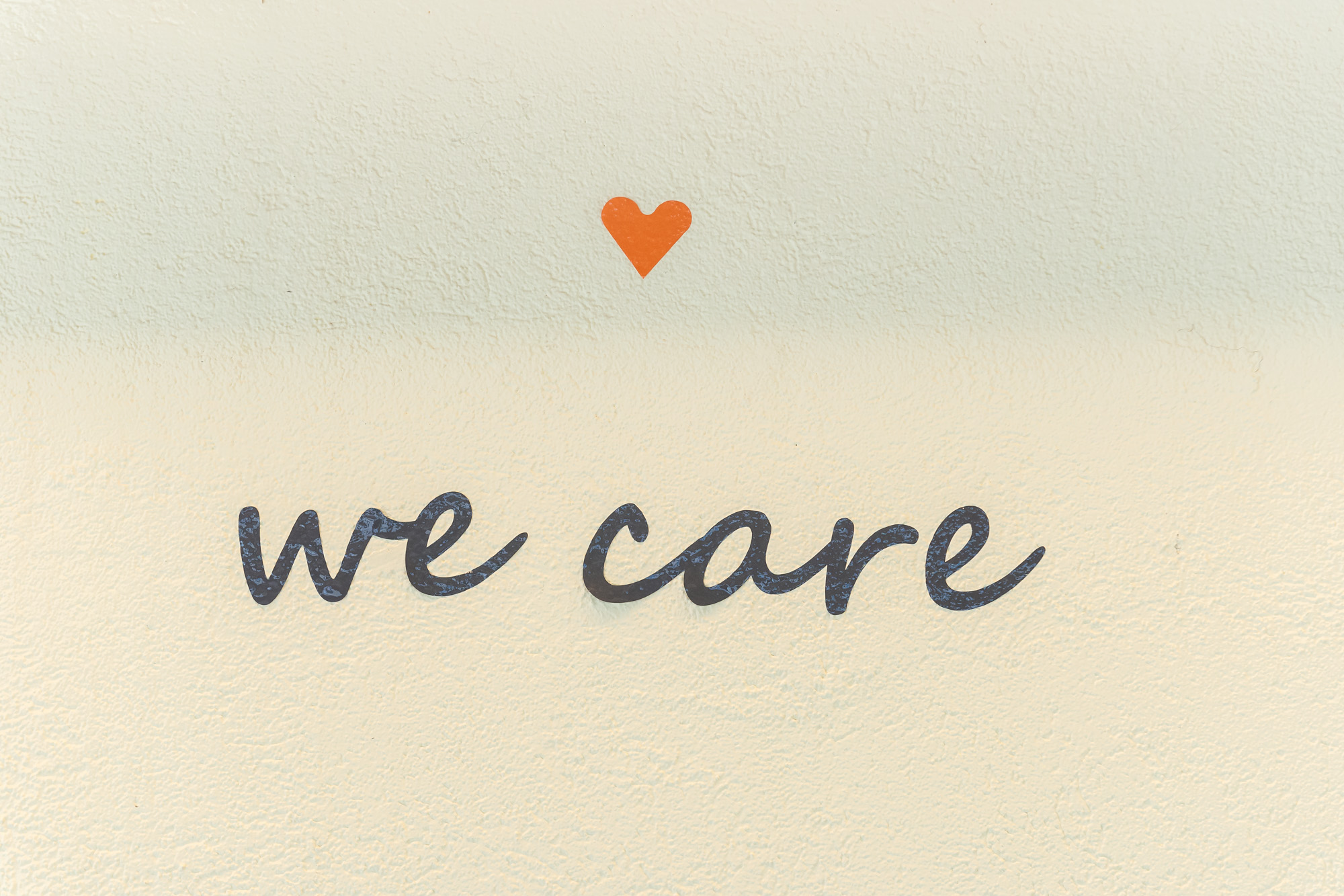 Scritta “we care” con sopra un cuoricino arancione
